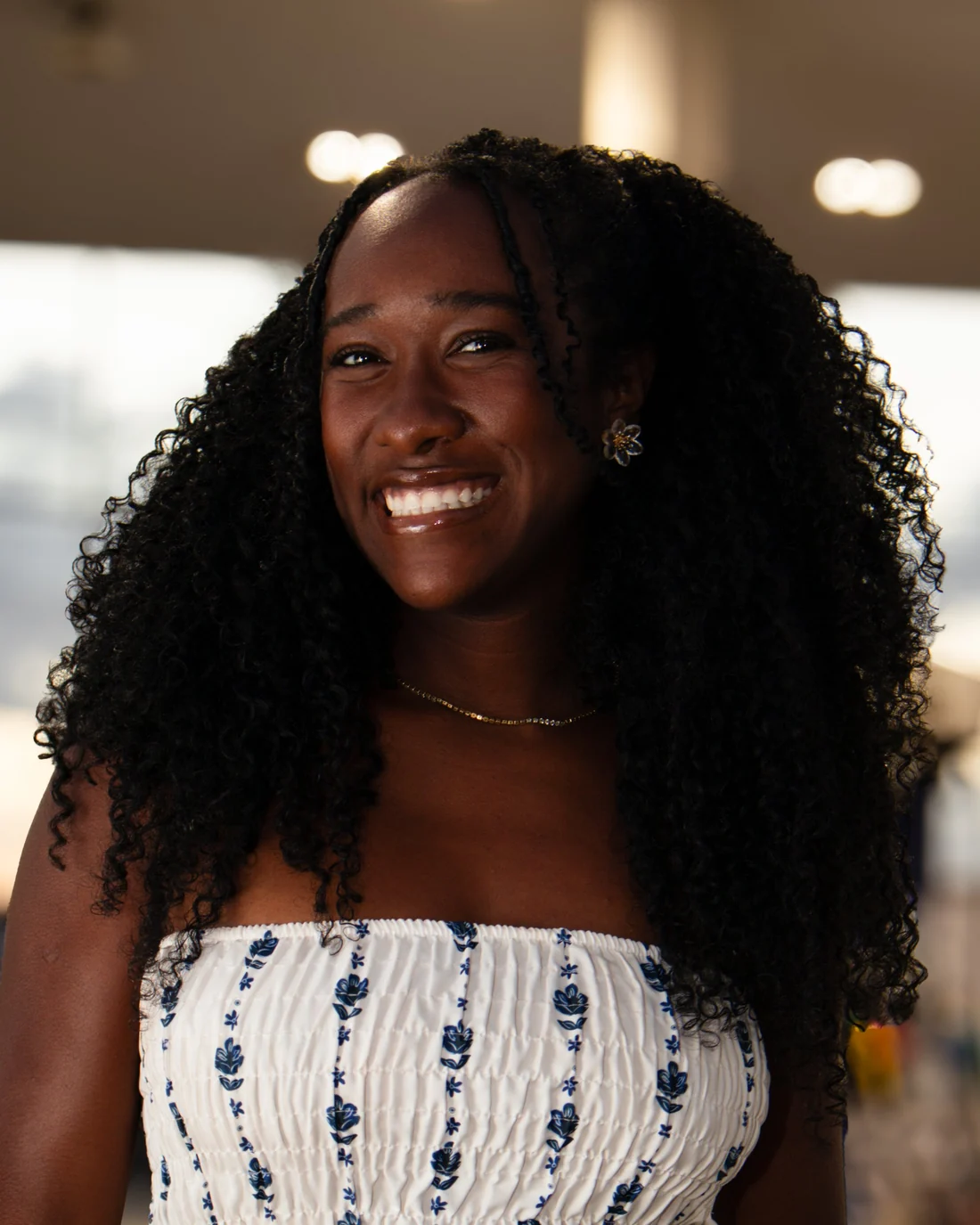 Karina, da equipe da Dendê Studio, sorrindo com o cabelo cacheado solto